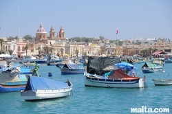 luzzu-in-the-harbour-of-marsaxlokk-and-the-parish-church-in-the-background